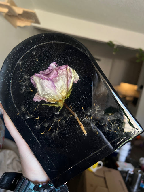 Dried flower on a black surface held by a hand with a blurred background